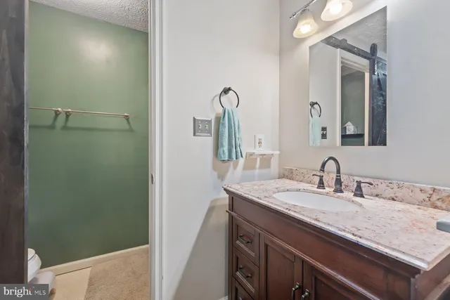 a bathroom with a granite countertop sink and a mirror