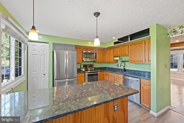 a kitchen with stainless steel appliances granite countertop a refrigerator a sink and a stove