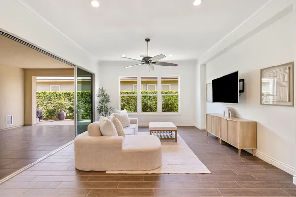 a living room with furniture a flat screen tv and a floor to ceiling window