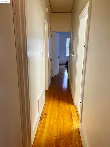 a view of a hallway with wooden floor and a bathroom