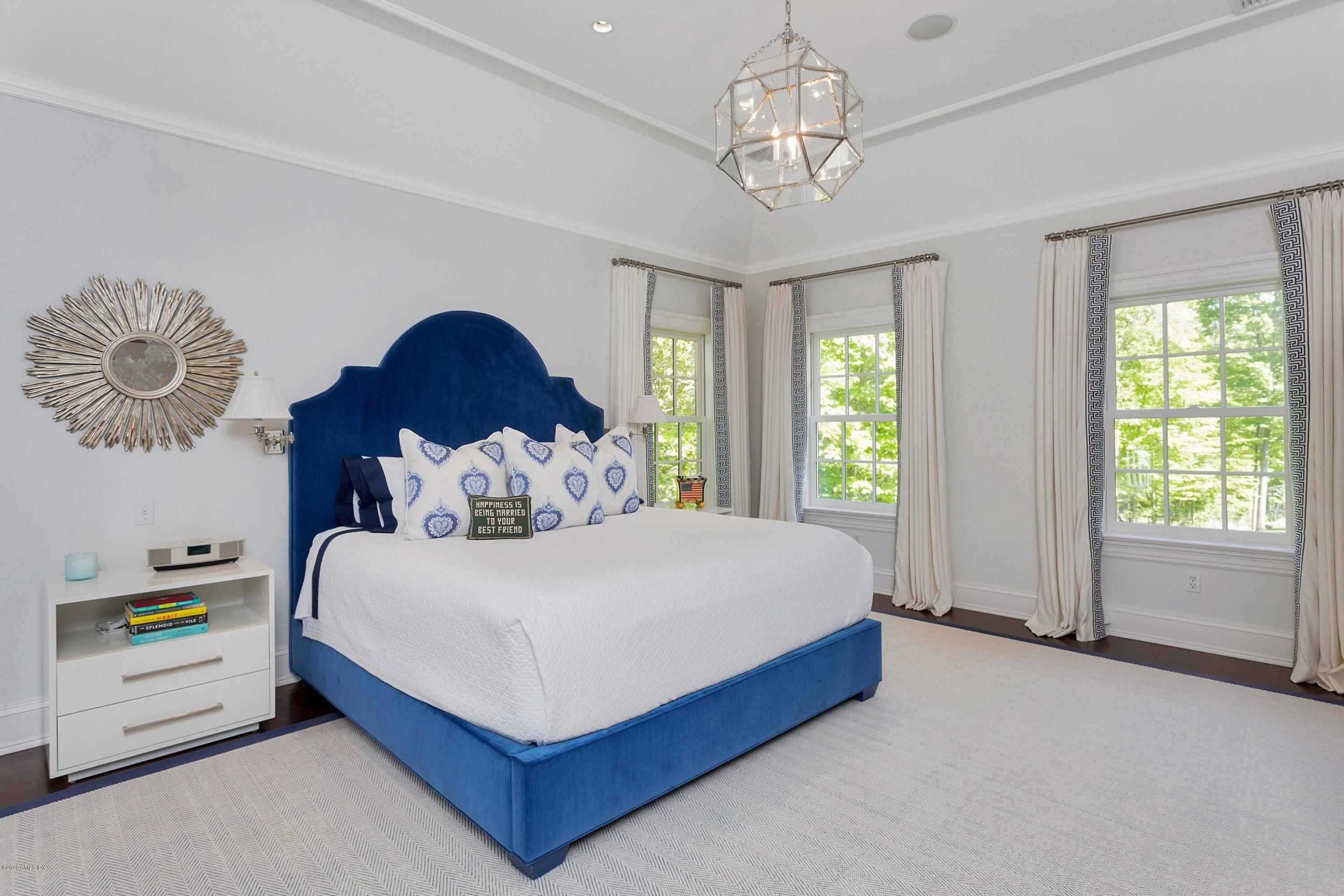 122 Butternut Hollow Road Greenwich, CT 06830 - Photo 21 of 36 a spacious bedroom with a bed and a chandelier
