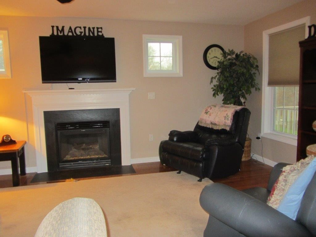 1161 B Mammoth Road, Unit B Pelham, NH 03076 - Photo 7 of 14 a living room with furniture a fireplace and a flat screen tv