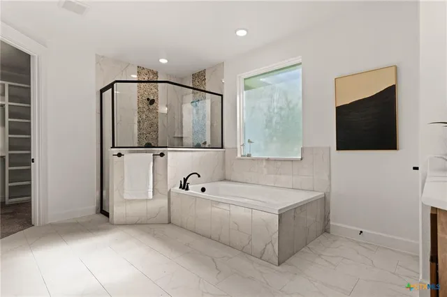 a spacious bathroom with a tub a mirror and tv