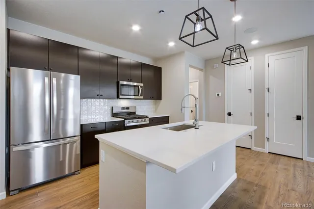 a kitchen with kitchen island a counter space a sink appliances and cabinets