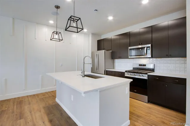 a kitchen with a sink stainless steel appliances a refrigerator and a stove top oven