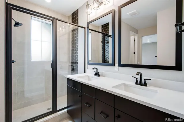 a bathroom with a double vanity sink mirror and shower