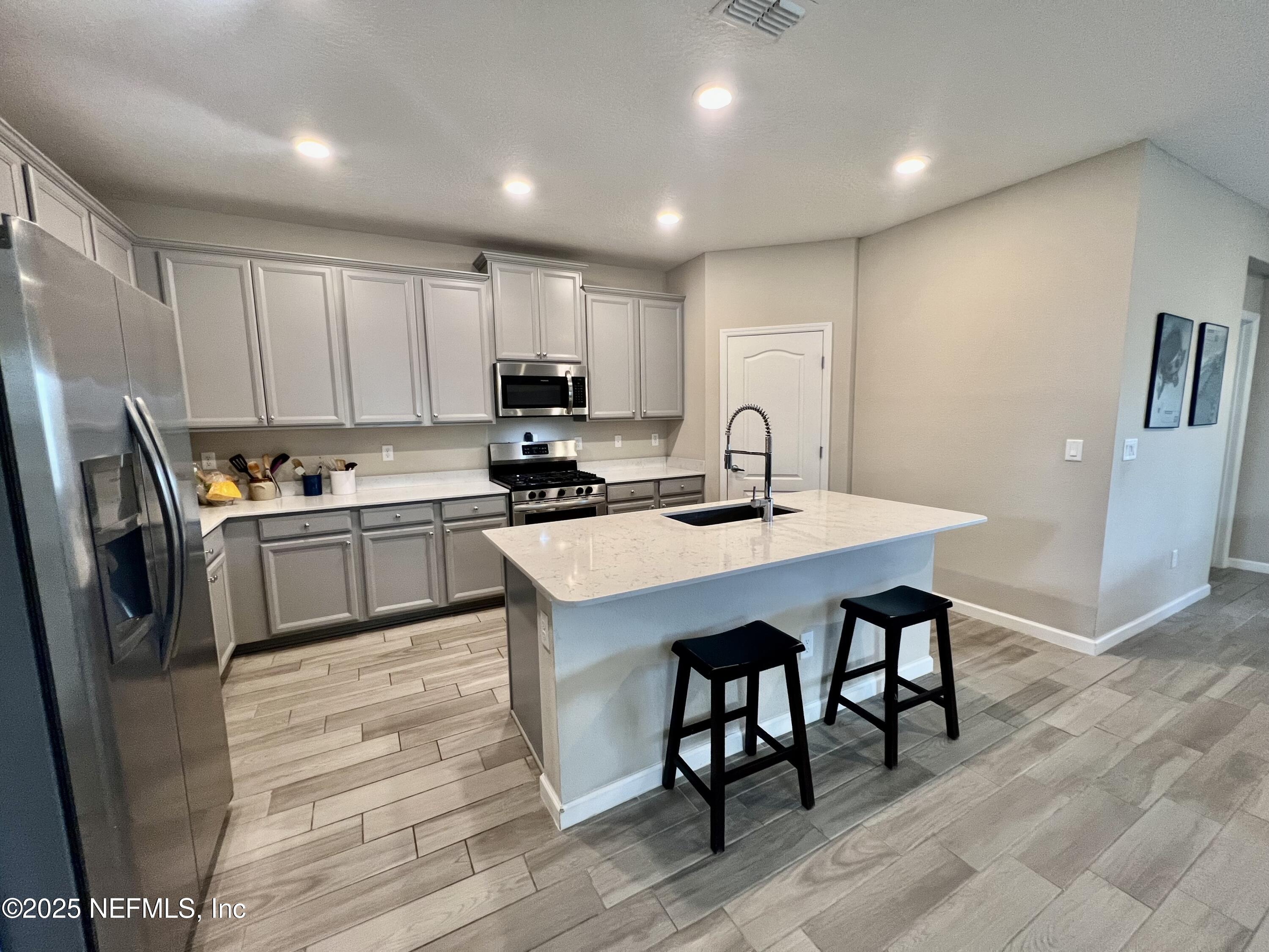 128 Ash Breeze Cove St. Augustine, FL 32095 - Photo 7 of 57 a kitchen with a sink a microwave a refrigerator and white cabinets