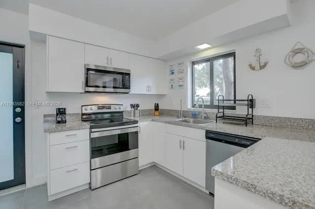 a kitchen with granite countertop a stove sink and microwave