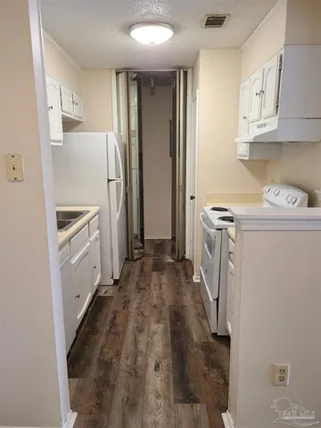 a kitchen with a refrigerator a stove top oven and cabinets
