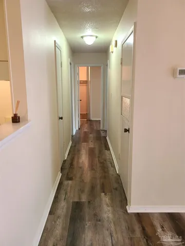 a view of a hallway with wooden floor and a bathroom
