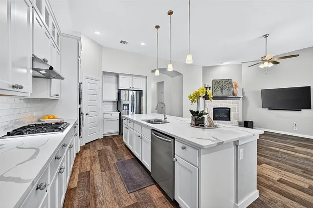 a kitchen with a sink a counter top space stainless steel appliances and a chandelier