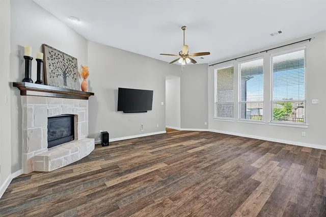 a view of an empty room with wooden floor fireplace and a window