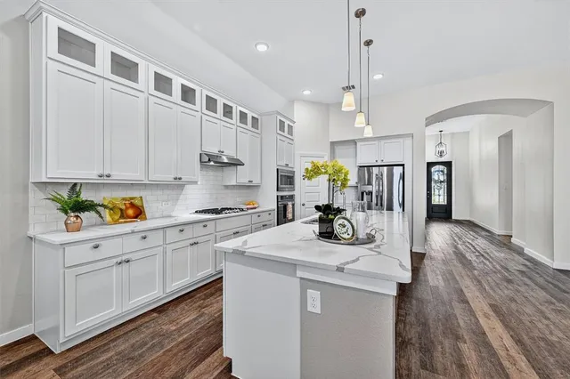 a kitchen that has a lot of cabinets in it and wooden floors
