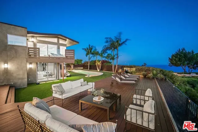 a view of a patio with couches table and chairs with potted plants and wooden fence