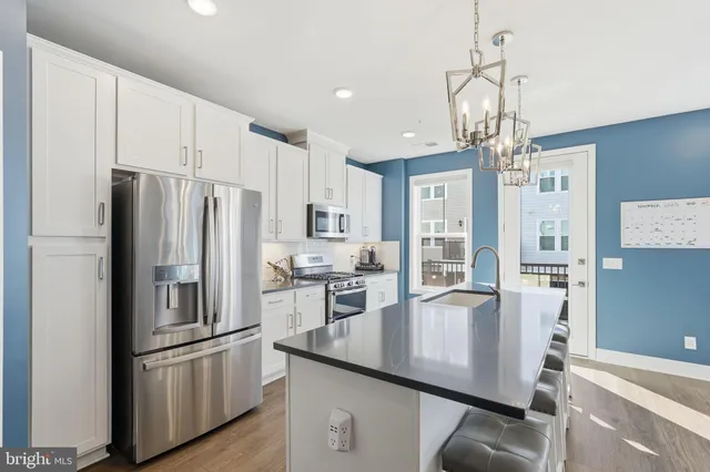 a kitchen with stainless steel appliances granite countertop a refrigerator a stove a sink dishwasher a stove with white cabinets and wooden floor