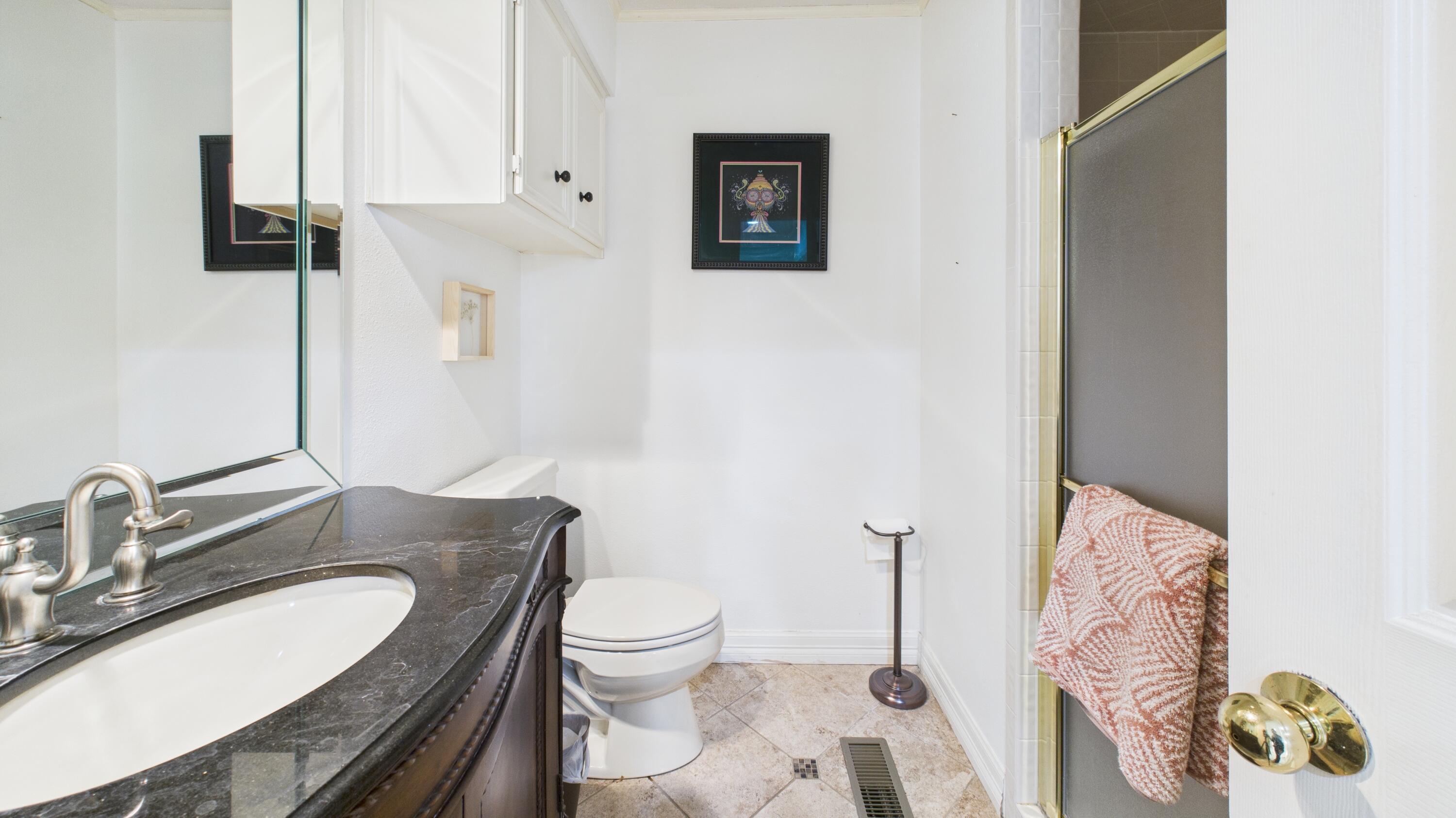 4615 94th Street Lubbock, TX 79424 - Photo 49 of 82 a bathroom with a granite countertop toilet sink and mirror