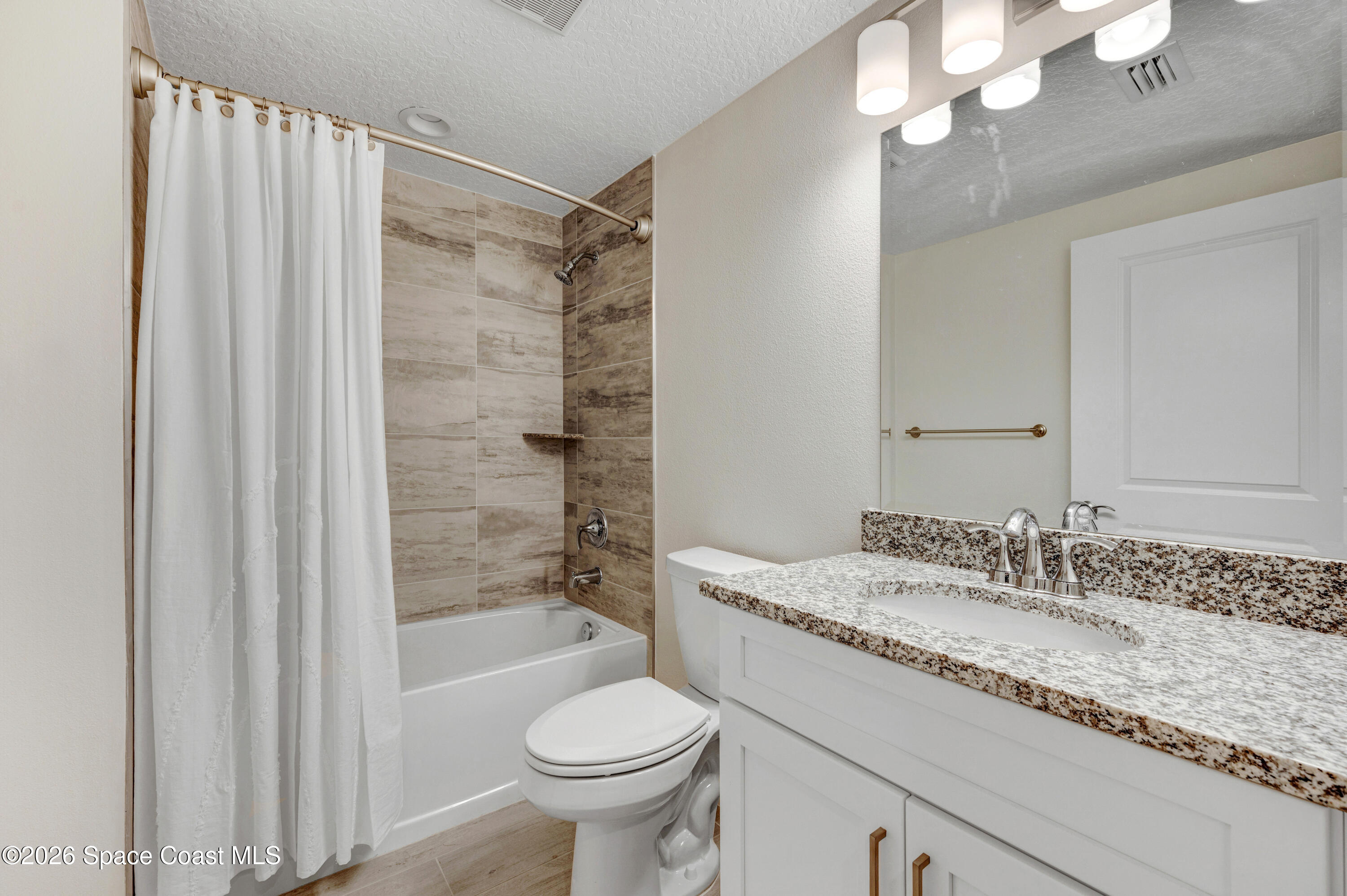 1805 Riverside Drive, Unit 304 Titusville, FL 32780 - Photo 23 of 46 a bathroom with a granite countertop sink a toilet a mirror and shower