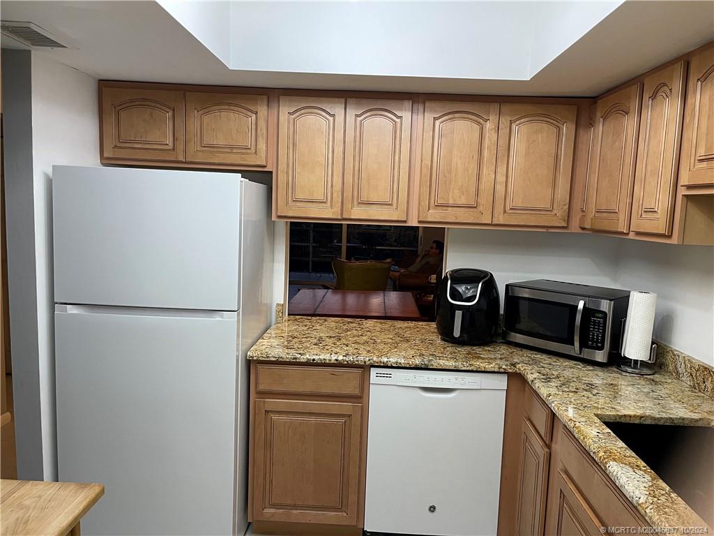 1900 South Kanner Highway, Unit 9202 Stuart, FL 34994 - Photo 13 of 55 a kitchen with granite countertop stainless steel appliances a refrigerator sink and cabinets