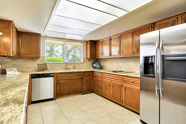a large kitchen with stainless steel appliances granite countertop a large counter top a stove and a refrigerator