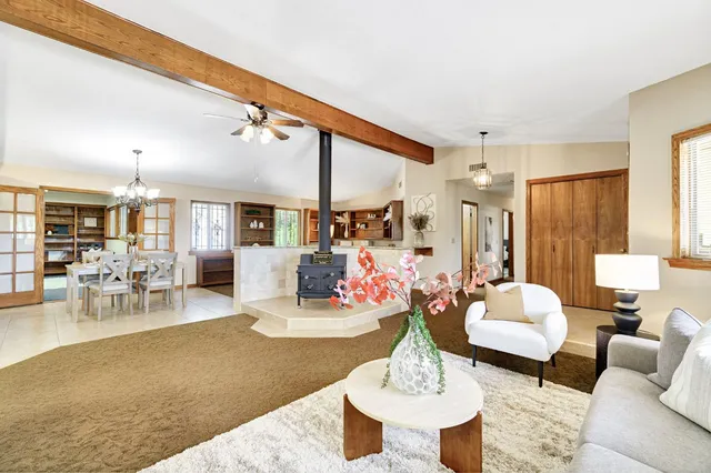 a living room with furniture a rug kitchen view and a large window