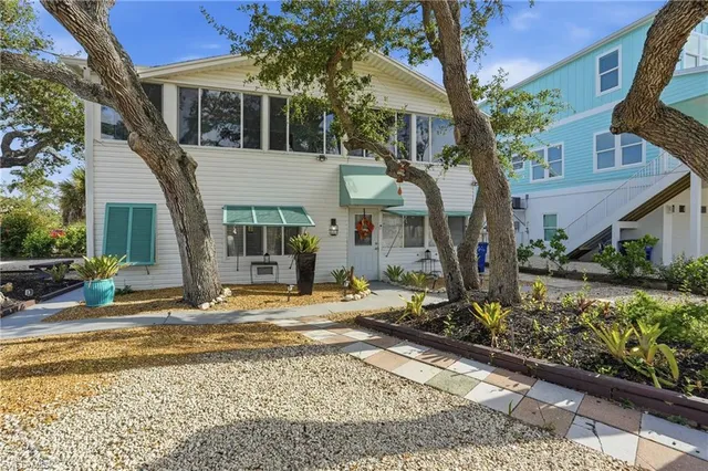 a view of a house with street chairs and a tree