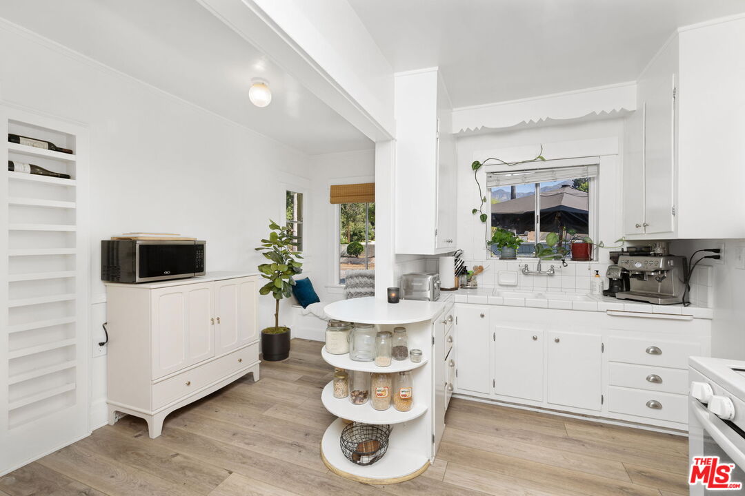 1732 Fiske Avenue Pasadena, CA 91104 - Photo 10 of 23 a kitchen with a white stove top oven and white cabinets with wooden floor
