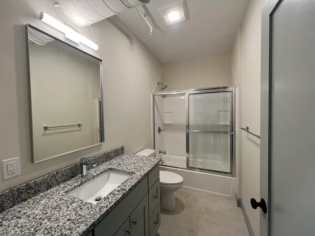 a bathroom with a granite countertop sink toilet and shower