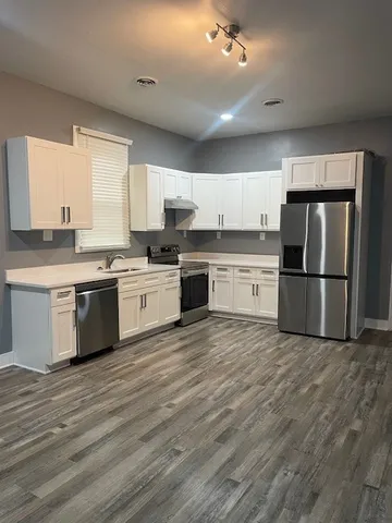 a large kitchen with cabinets stainless steel appliances and a window