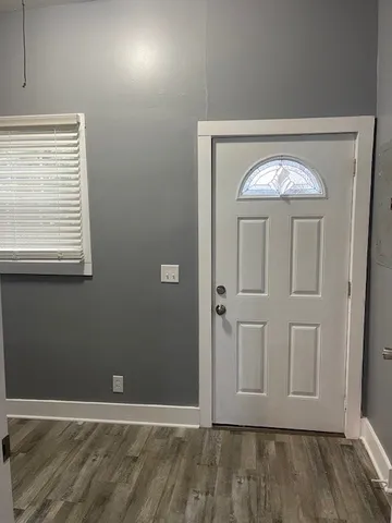 an empty room with wooden floor cabinet and windows