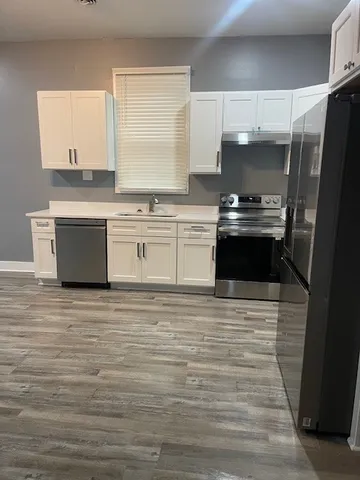 a kitchen with stainless steel appliances wooden floor sink stove and cabinets