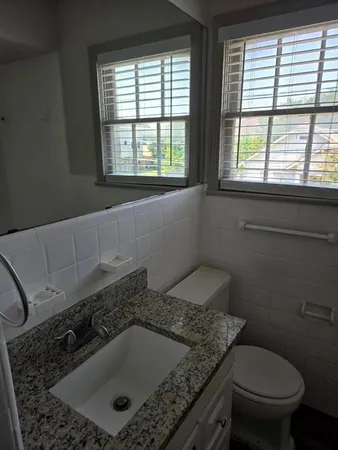 a bathroom with a granite countertop sink a toilet and a window