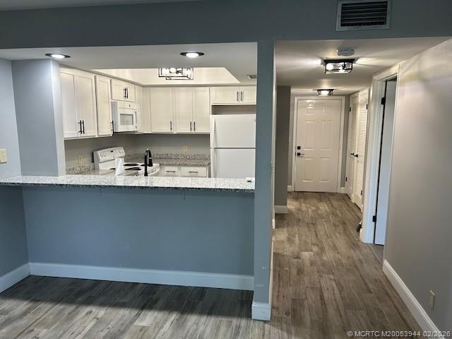 803 Southeast Central Parkway, Unit 5 Stuart, FL 34994 - Photo 1 of 19 a kitchen with kitchen island white cabinets and wooden floor