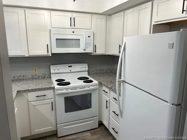 a kitchen with white cabinets and white appliances