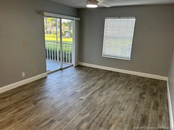 a view of an empty room with wooden floor and a window