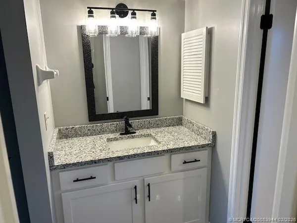 a bathroom with a granite countertop sink and a mirror