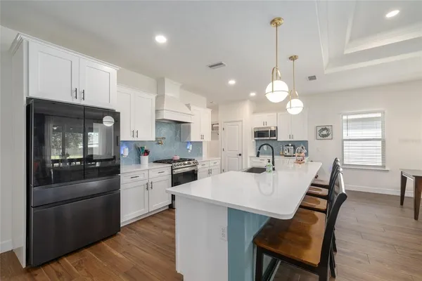 a large kitchen with kitchen island a stove a sink a dining table and chairs