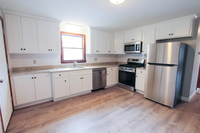 a kitchen with white cabinets stainless steel appliances and window