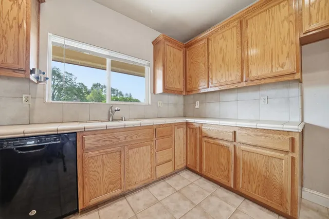 a kitchen with stainless steel appliances granite countertop a stove top oven a sink dishwasher and a refrigerator with wooden cabinets