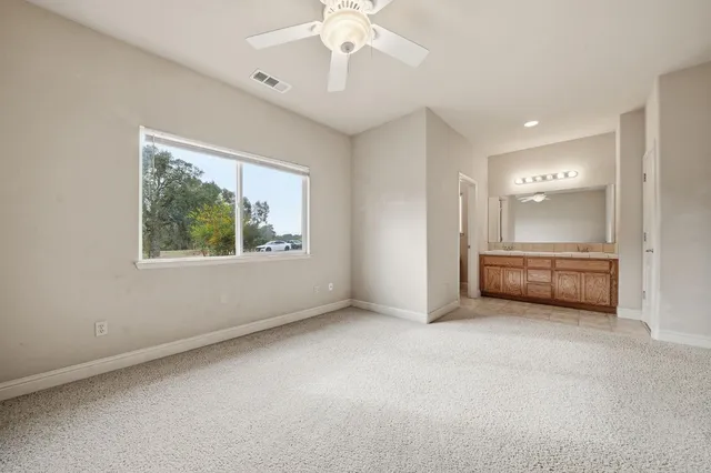 an empty room with chandelier fan and windows