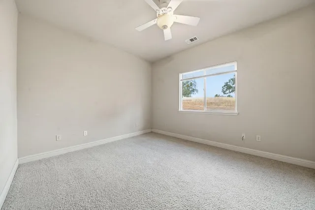 an empty room with a chandelier fan and closet area