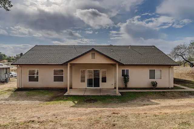 a front view of a house with a garden and trees