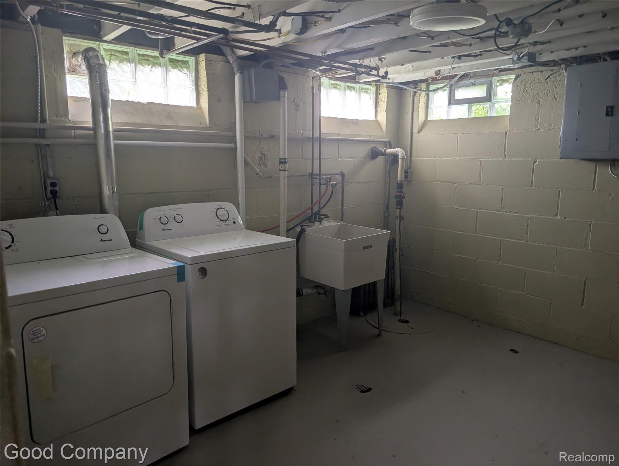 Utility area with concrete block walls, utility sink, and glass block windows