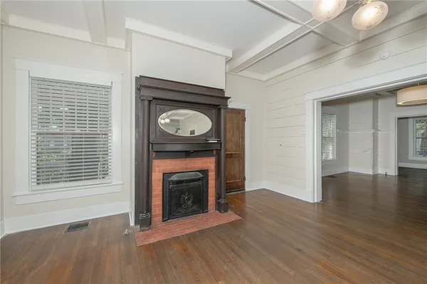 a view of an empty room with wooden floor fireplace and a window