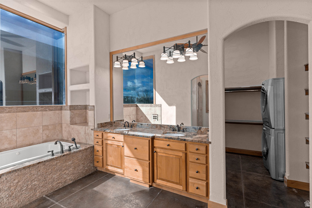 2464 East Granite Way St. George, UT 84790 - Photo 35 of 106 Primary full bathroom featuring double vanity, stacked washing machine and dryer, a spacious closet, a bath, and dark tile patterned floors
