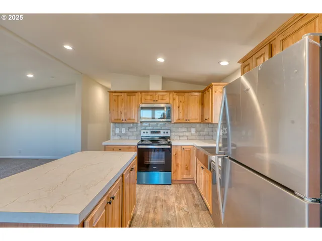 a kitchen with stainless steel appliances granite countertop a refrigerator a stove and a sink
