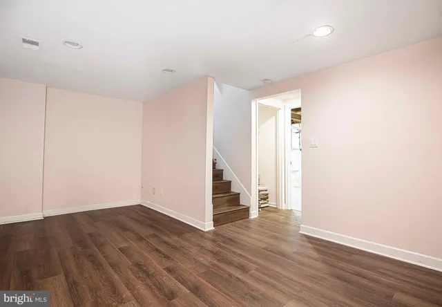 a view of an empty room with wooden floor and stairs