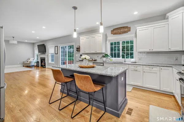 a kitchen with stainless steel appliances granite countertop a sink a stove a dining table and chairs