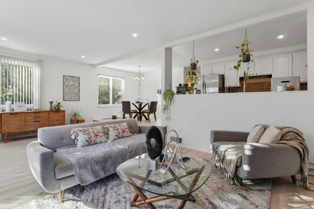 a living room with furniture and a dining table with wooden floor