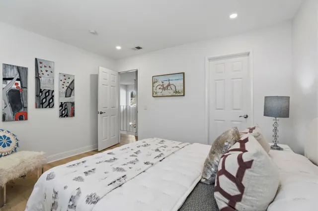 a bedroom that has a bed and paintings on the dresser