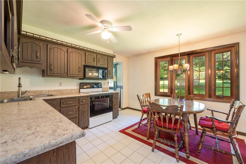 756 Arona Road New Stanton, PA 15672 - Photo 6 of 35 a kitchen with stainless steel appliances granite countertop a stove top oven a sink dishwasher a dining table and chairs with wooden floor